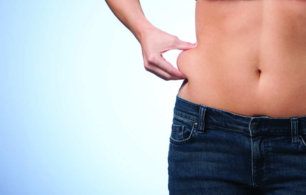 Woman pinching fat on muffin top area